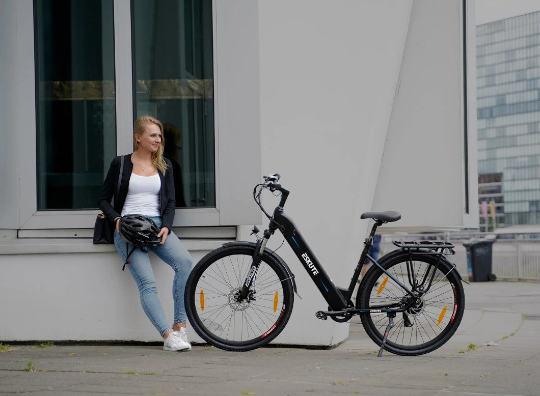 Woman sitting beside a black Eskute Polluno eBike on an urban street.