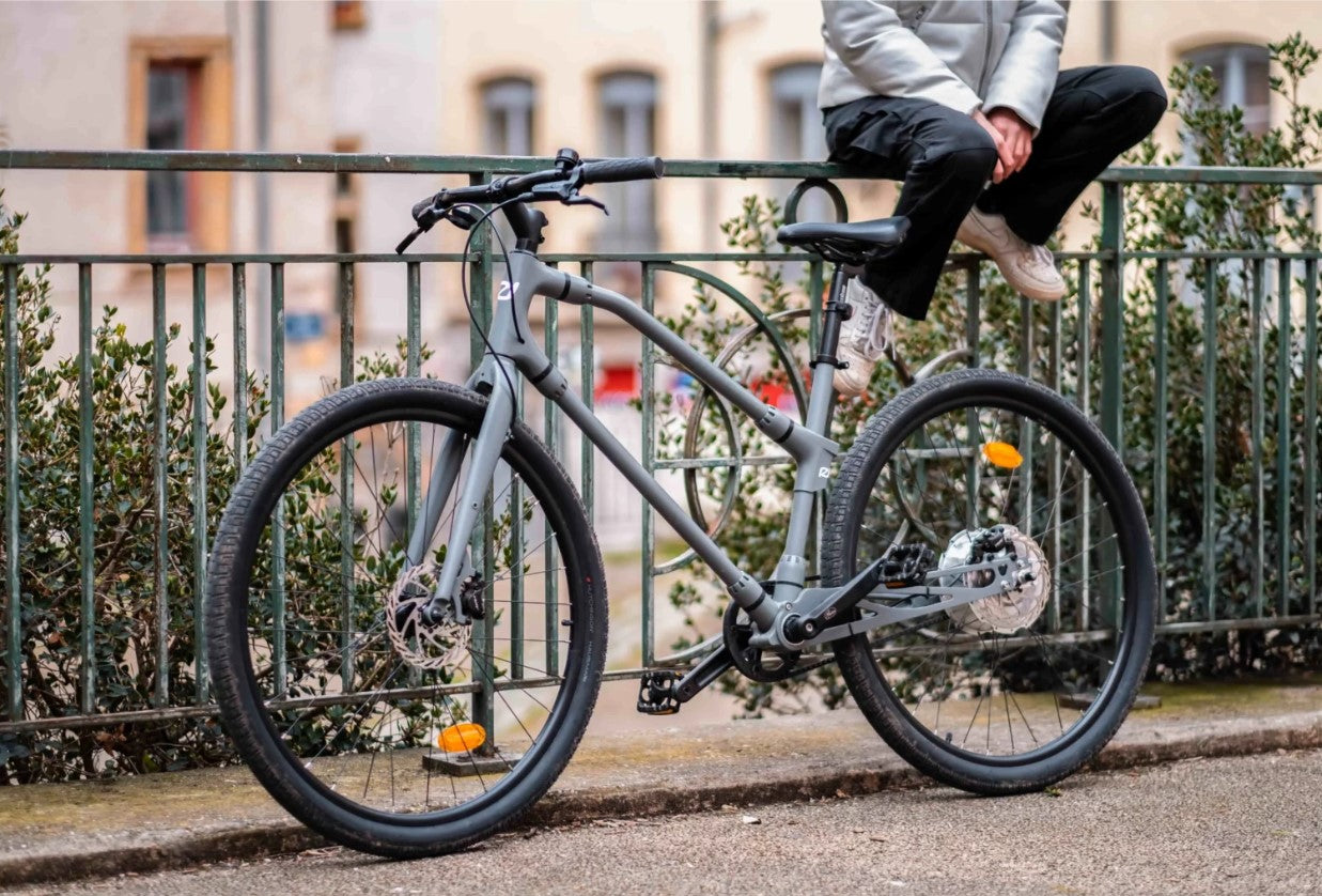 Person casually sitting next to Essential Boost  bike, illustrating its use in everyday urban life.