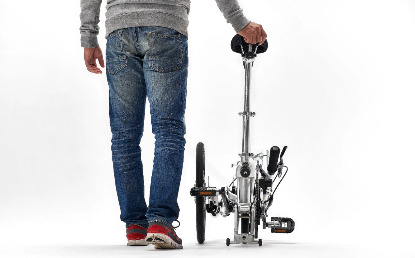 Person walking with folded Iruka C Ebike, illustrating ease of transport.