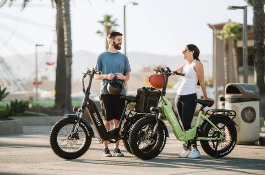 Man and woman chatting outdoors next to folding Eskute e-bikes, showcasing portability and urban healthy lifestyle.