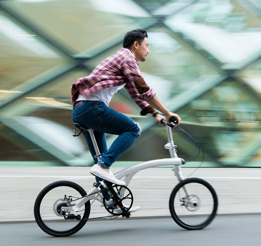 Man riding Iruka compact folding bike in urban setting, exemplifying the brand's commitment to stylish and sustainable city commuting.