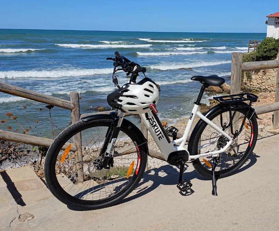 White Eskute Polluno Pro electric bicycle by the shore, showcasing its design and scenic location.