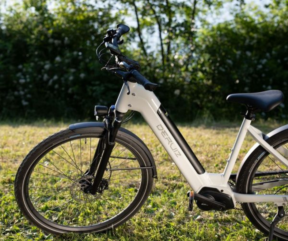 Mica-G ebike parked in a lush green field, showcasing its sleek white frame and modern design