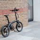 Eole S electric folding bike parked on a sidewalk, illustrating its sleek design and urban appeal.