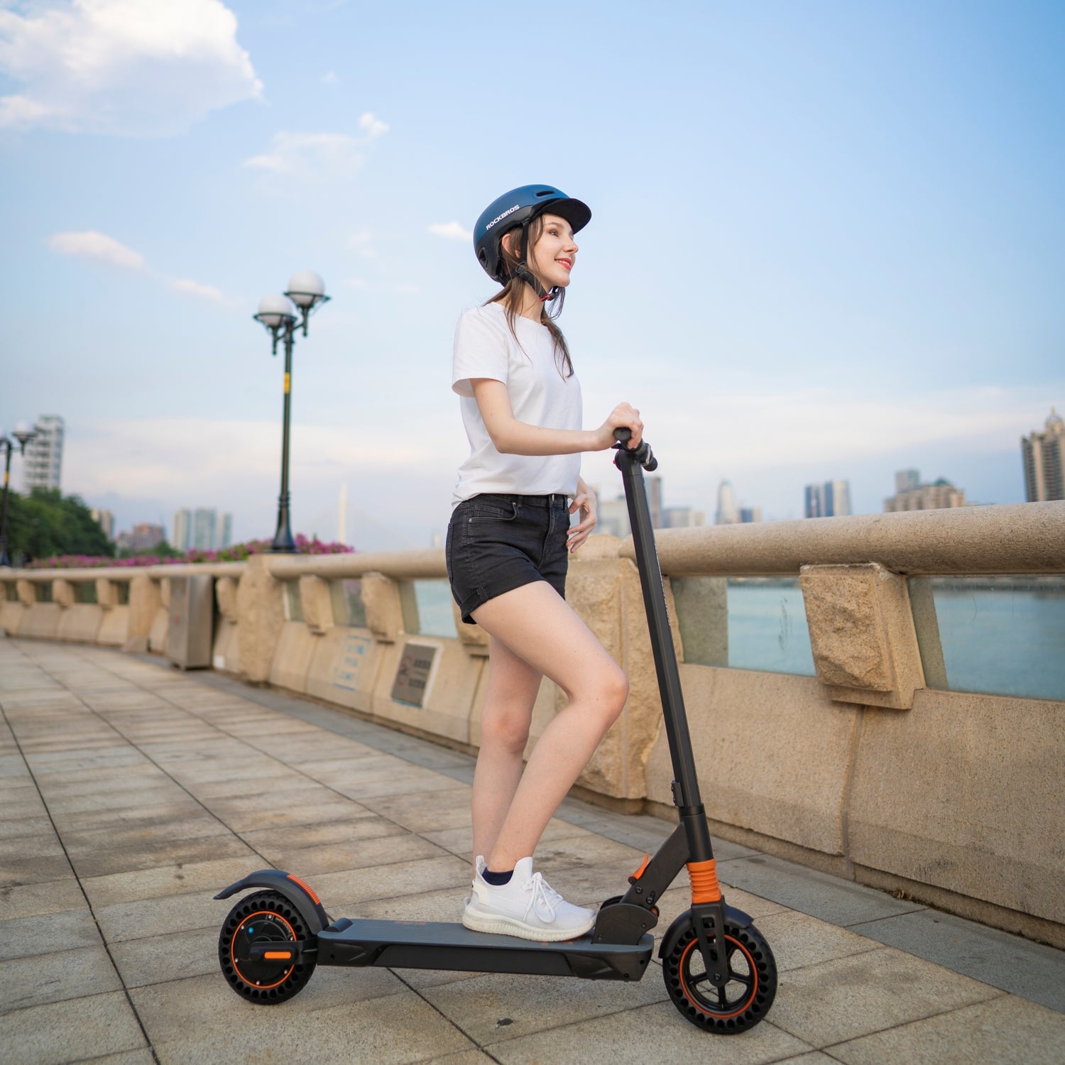 A woman riding the Kugoo Kirin S1 Pro Electric Scooter next to the riverside.